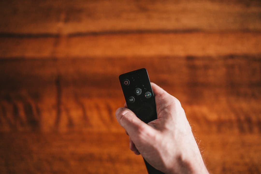 Main tenant une télécommande de clé de streaming devant un téléviseur